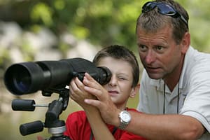 man teaching a boy to use a scope