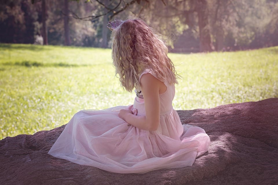girl in dress sitting under a tree